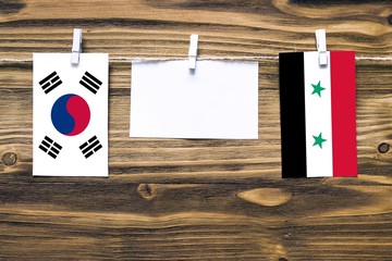 Hanging flags of South Korea and Syria attached to rope with clothes pins with copy space on white...