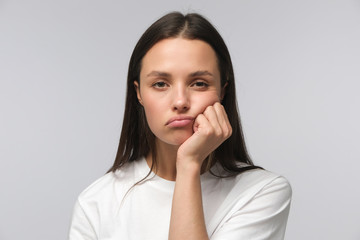 Fototapeta na wymiar Young woman pressing hand to chin, looking bored, exhausted and disappointed, feeling helpless and upset, isolated on gray background