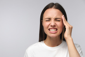Headache concept. Young woman showing how much her head hurts, experiencing pain, looking miserable...