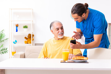 Young male doctor visiting old patient at home