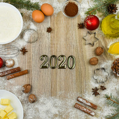 Tools and products for baking homemade gingerbread cookies on a wooden background with the inscription 2020. The concept of the holiday, celebration and cooking. New Year and Christmas card. 