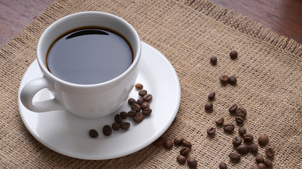 cup of coffee and coffee beans on jute