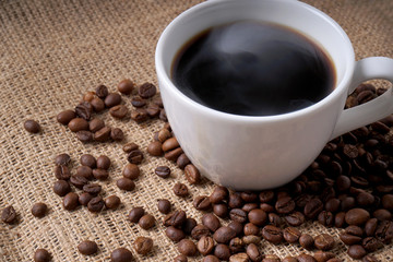 cup of coffee and coffee beans on jute