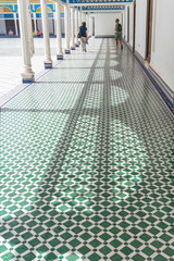 Couple stepping on the geometric decorative floor in the courtyard of the Bahia palace in Marrakech. Morocco