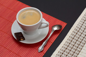 Cup of coffee with chocolate bar and spoon.