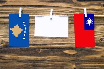 Hanging flags of Kosovo and Taiwan attached to rope with clothes pins with copy space on white note paper on wooden background.Diplomatic relations between countries.