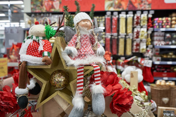 Shelf in a store with a clearance sale for Christmas or New Year 2020 in a store with decor. Stuffed toy girls and wooden stars on the background of shelves in the store