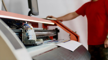 Operator works on computer by setting print options. Typography worker printing production on computerized modern printing press. Printmaker using ciss system for inkjet printer. Publishing industry. - obrazy, fototapety, plakaty