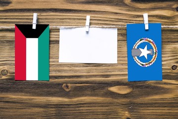 Hanging flags of Kuwait and Northern Mariana Islands attached to rope with clothes pins with copy...