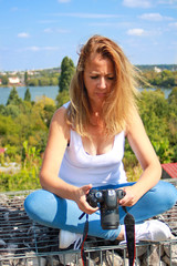 Fototapeta na wymiar Long-haired blonde sexy woman with a SLR camera. Girl using technology.