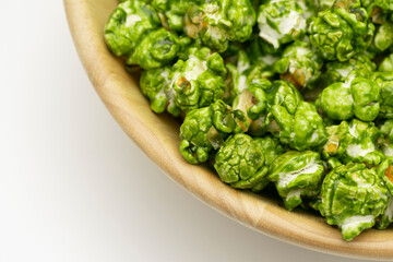 Top view of lush Japanese matcha green tea popcorn in the wooden bowl bulk isolated on white background, Popular snack with favorite movie