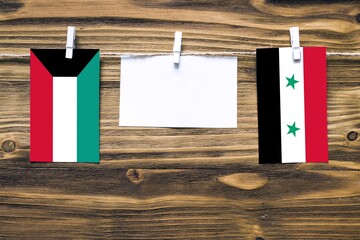 Hanging flags of Kuwait and Syria attached to rope with clothes pins with copy space on white note...