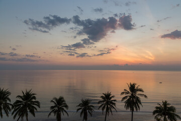 Fototapeta na wymiar Tranquil sunrise in Hua Hin beach with coconut trees, Thailand