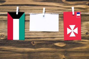 Hanging flags of Kuwait and Wallis And Futuna attached to rope with clothes pins with copy space on...