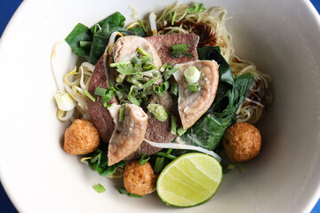 Noodles with boiled pork Consisting of pork offal ,Meatballs and bean sprouts sprinkled with sliced onions and lemon slide