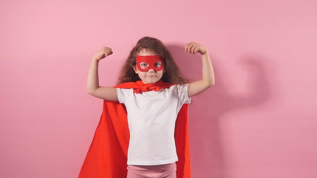 Portrait of strong little girl in superhero cloak and mask.