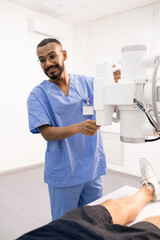 Young smiling doctor in blue uniform using new medical equipment