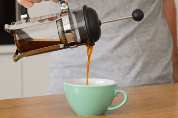 Kaffee aus einer Frenchpress in eine grüne Tasse eingießen