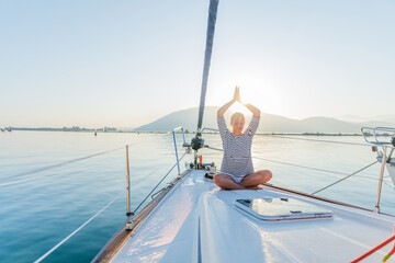 Girl is practicing yoga on the deck of the yacht boat