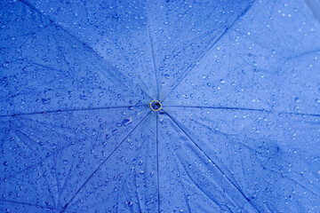 Top view background and texture of raindrops on blue umbrella.
