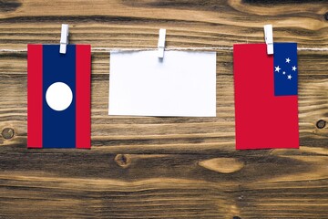 Hanging flags of Laos and Samoa attached to rope with clothes pins with copy space on white note...