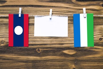 Hanging flags of Laos and Sierra Leone attached to rope with clothes pins with copy space on white...