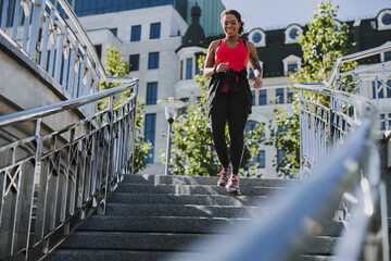 Joyful Afro American lady running down the stairs outdoors