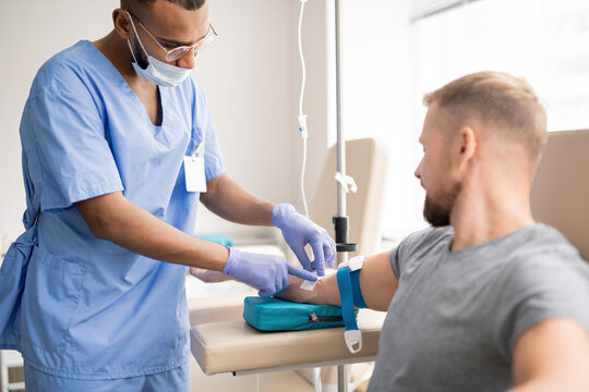 Contemporary doctor preparing arm of sick patient for dropper injection