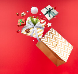 Happy New year shopping magic concept. Christmas paper bag, gifts, Lollipop, decorations and toys are flying in the air on a red background. Copy space.