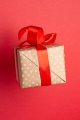 Gift box in white dotted with red ribbon on red background