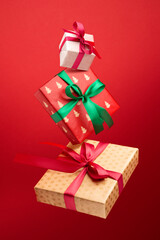 Christmas shopping concept. Gift boxes are flying in the air and hand-lettering Merry Christmas on a red background.
