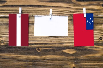 Hanging flags of Latvia and Samoa attached to rope with clothes pins with copy space on white note...