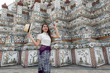 Young Asian women tourist traveling at Wat Arun Ratchawararam, one of the famous places in Bangkok, Thailand