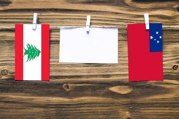 Hanging flags of Lebanon and Samoa attached to rope with clothes pins with copy space on white note...