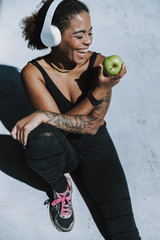 Cheerful Afro American girl in headphones eating apple