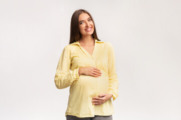Obraz premium Smiling Pregnant Woman Touching Belly Standing Over White Background