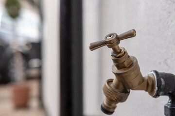 Close-up, isolated image of the handle of a brass coloured outside water tap, attached the the...