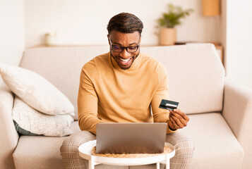 Guy Using Credit Card And Laptop Sitting On Sofa Indoor