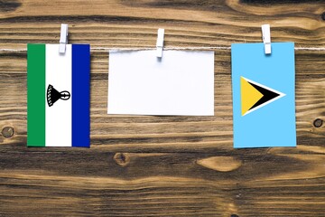 Hanging flags of Lesotho and Saint Lucia attached to rope with clothes pins with copy space on...