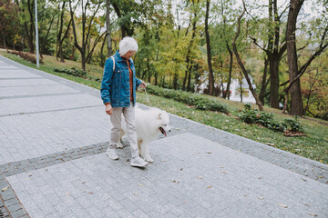 Happy mature woman walking with pet in park
