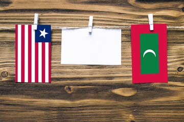 Hanging flags of Liberia and Maldives attached to rope with clothes pins with copy space on white...