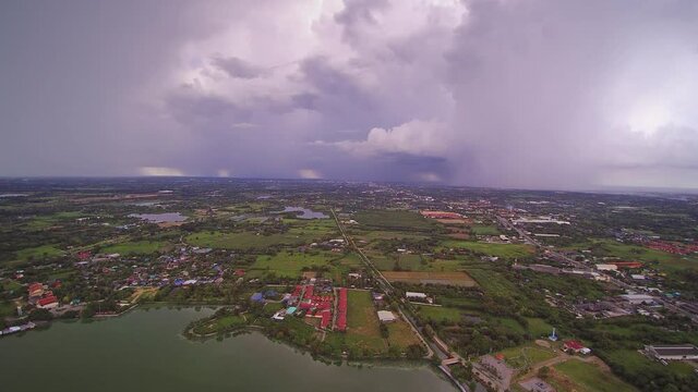 Aerial view above the lake of rain storm with heavy raining above villages and rice paddy fields, Krajub reservoir, Nong Kop District, Ban Pong, Ratchaburi, Thailand.