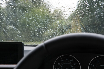 Drivers view of a heavy downpour seen will parking up in a luxury, german-built sports car.
