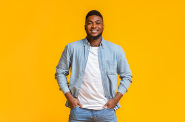 Portrait of handsome black guy standing with hands in pockets