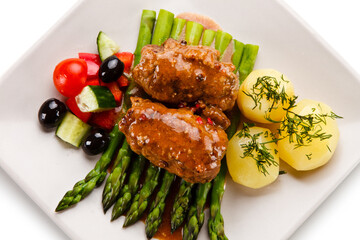 Wrapped pork chops with potatoes and asparagus on white background