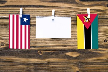 Hanging flags of Liberia and Mozambique attached to rope with clothes pins with copy space on white...