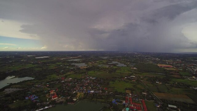 Aerial view above the lake of rain storm with heavy raining above villages and rice paddy fields, Krajub reservoir, Nong Kop District, Ban Pong, Ratchaburi, Thailand.
