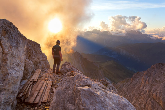 A hiker oberves a cloudy sunset from the summit of Cima di Costabella, Costabella Ridge, Marmolada group, Dolomites, Moena, Fassa Valley, Trento province, Trentino-Alto Adige, Italy.