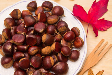 plate of chestnuts on wood and dried leaves