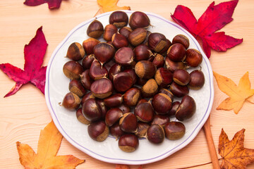 plate of chestnuts on wood and dried leaves